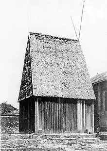 Large wooden house with a steeply peaked roof sixty feet high made of thatch