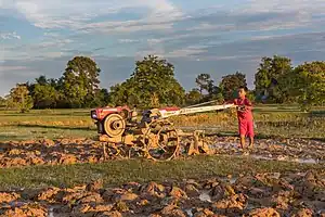 Boy plowing with a tractor at sunset in Don Det