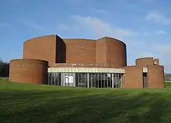 An almost windowless brick building made up of several circular sections of various sizes