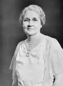 Photograph of a woman wearing a necklace and eyeglasses.