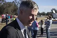 Colour photo of a man wearing a suit at an outdoor event