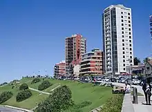 A street with a grassy ramp on one side and some tall buildings on the other.