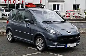 Front-three-quarter view of a three-door car with sliding passenger doors and front fog lamps