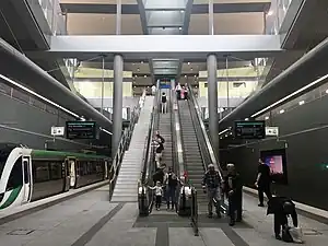 Underground station platform with escalators and stairs going up to ground level concourse