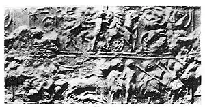 Seal from PG 1236 with inscription "Aja-Anzu", also read "A-Imdugud". Upper register: a nude hero fighting lions. Lower register: chariotter trampling an enemy, and foot soldiers escorting a naked prisoner.